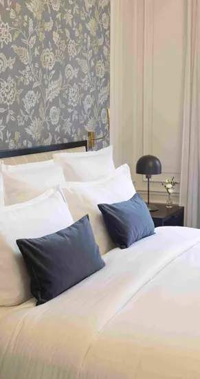 Bild eines gemachten Hotelbettes mit grauen Kissen