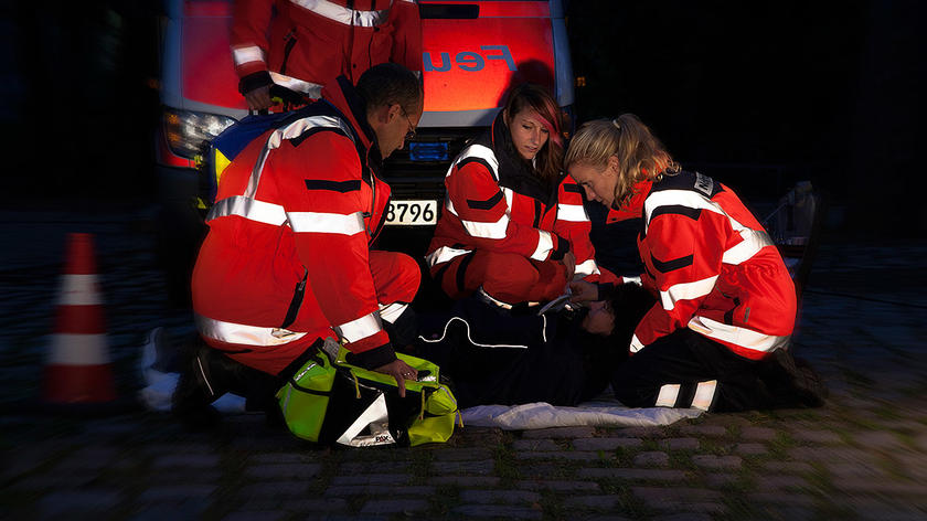 Bild eines Rettungsdienst Teams im Einsatz bei Nacht, die Rettungsdienstkleidung reflektiert gut sichtbar.