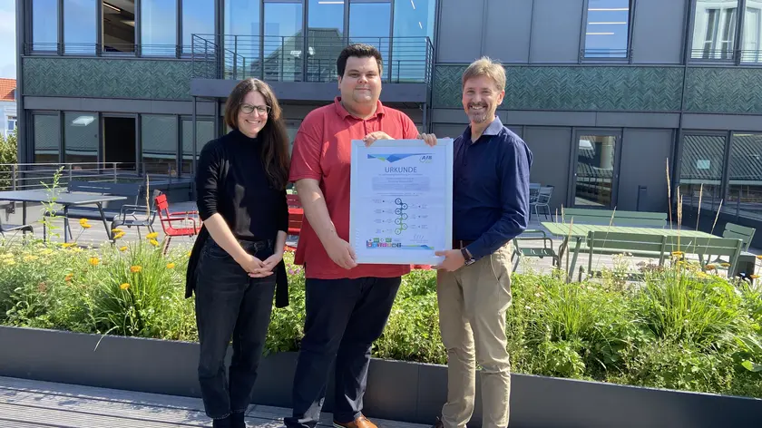 Übergabe der AfB-Urkunde (v.l.n.r.: Janina Heel (CSR Cluster Manager), Hendrik von Dankbahr (Head of IT - Support End User Services) und Jurij Deperschmidt (AfB)