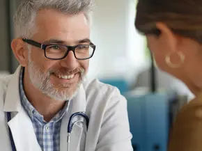 Bild eines lächelnden Arztes im Gespräch mit einer Patientin