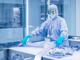 Bild einer Mitarbeiterin in einem Reinraum mit Schutzbrille