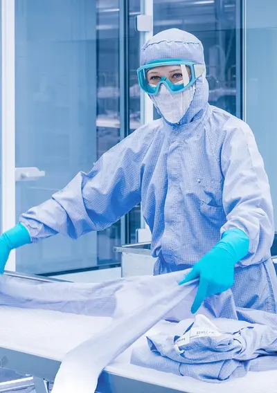 Bild einer Mitarbeiterin in einem Reinraum mit Schutzbrille