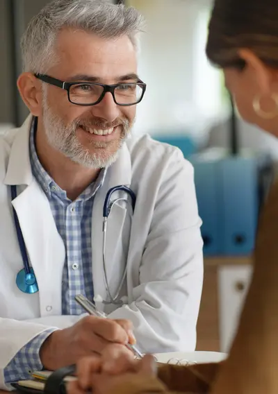 Bild eines lächelnden Arztes im Gespräch mit einer Patientin