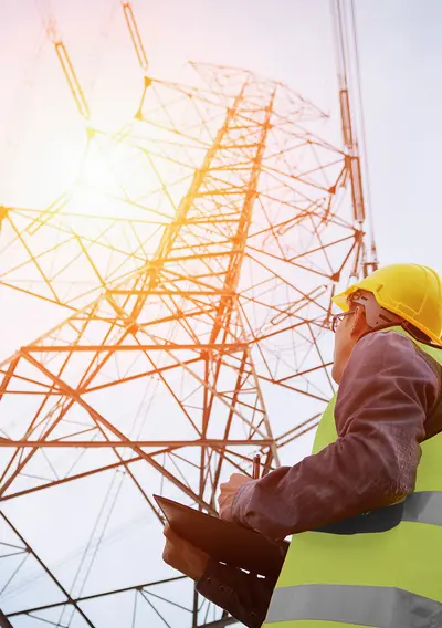 Bild eines Mannes in Warnschutzweste vor einem Strommast