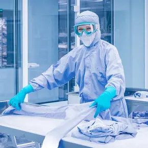 Bild einer Mitarbeiterin in einem Reinraum mit Schutzbrille
